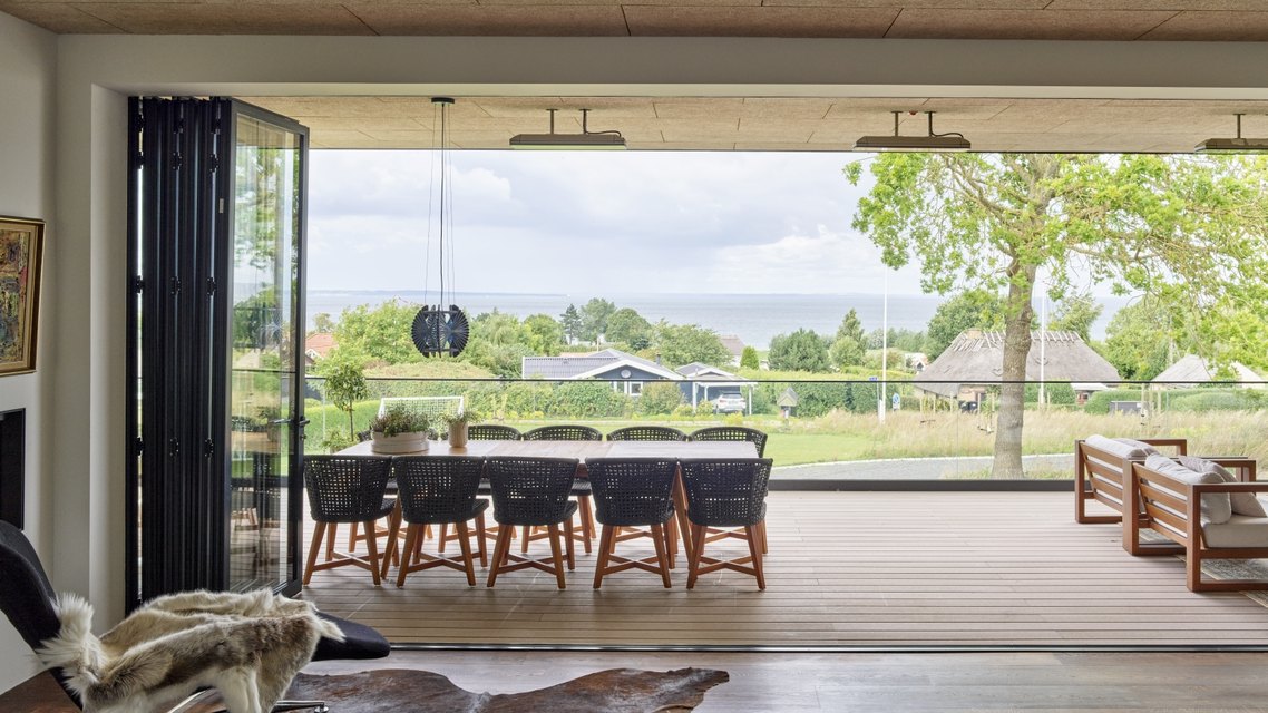 Large aluminium sliding system opening a contemporary living space to the landscape